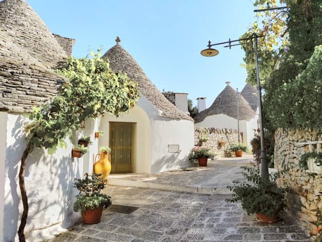 Stone trulli cottages with conical roofs among olive trees in sunny Puglia