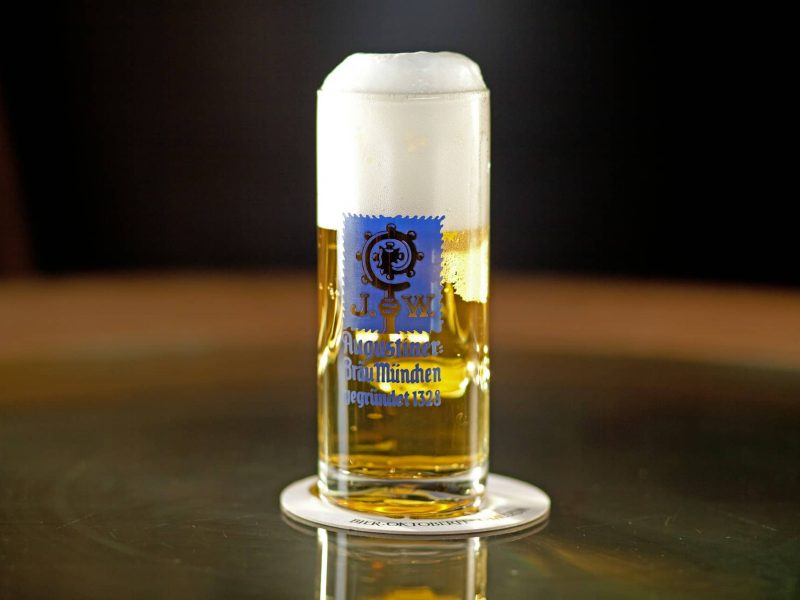 Visitors in traditional dirndl and lederhosen enjoying beer at Oktoberfest in a large Munich beer tent