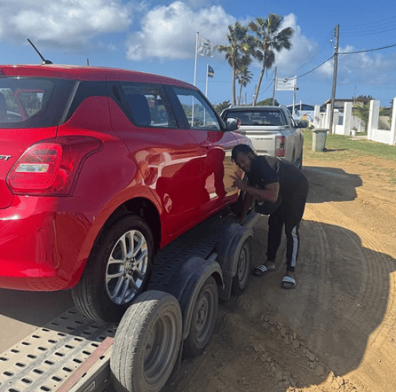 Car driving along a coastal road in Curaçao with blue sea and palm trees